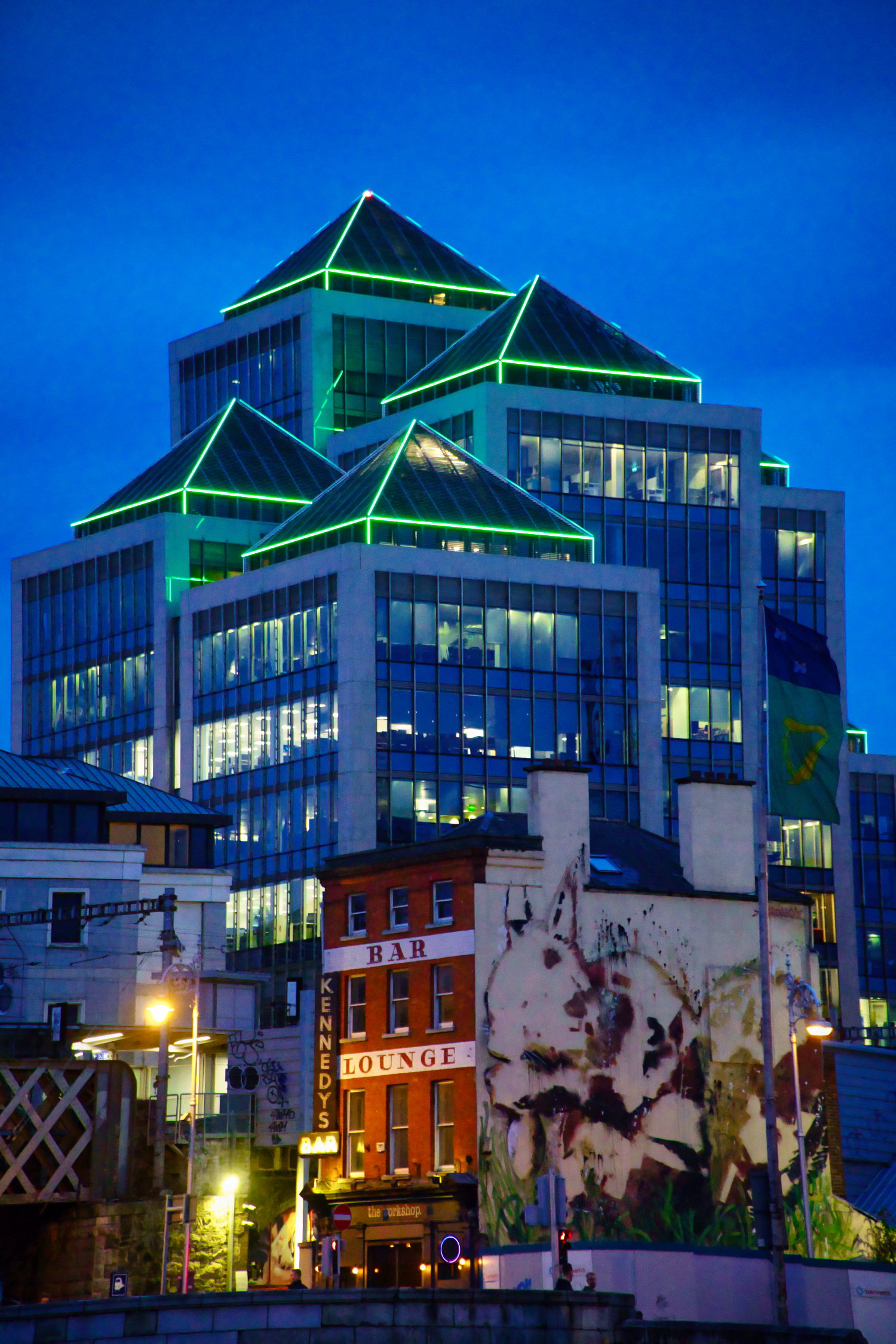 A picture showing an traditional irish bar with a modern tech office building behind it 